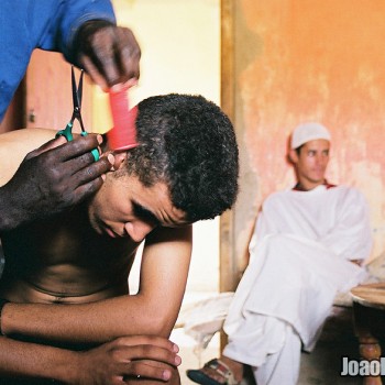 Man cutting the other one’s hair in Erg Chebbi Dunes, Sahara Desert South-East Morocco